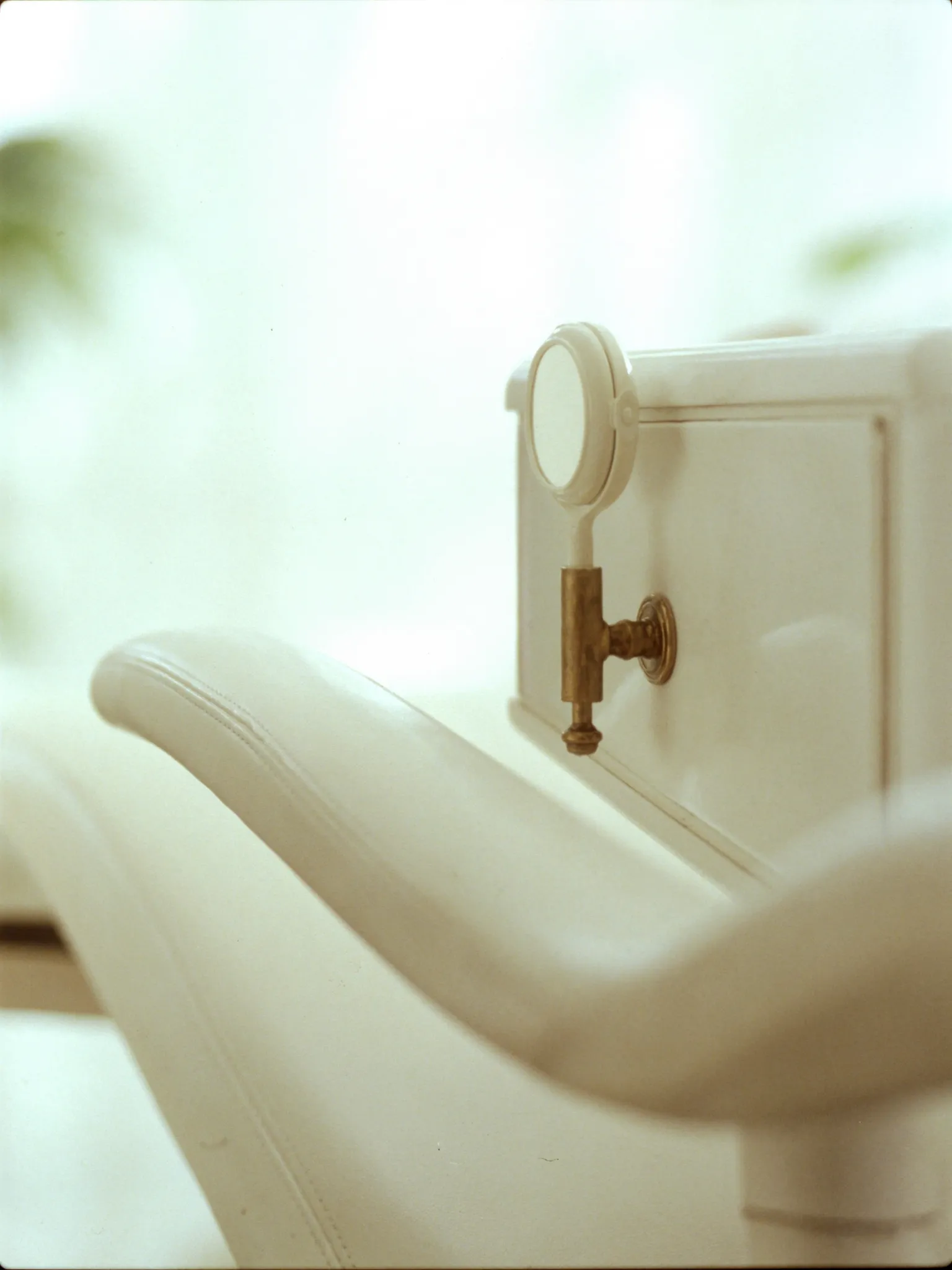 Detail of the treatment chair — cream leather stitching and a brass fixture
