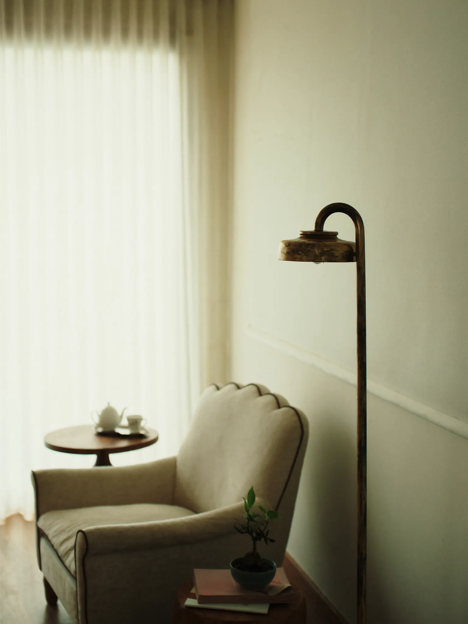 The reception lounge — a linen armchair, tea service, and brass lamp in soft light
